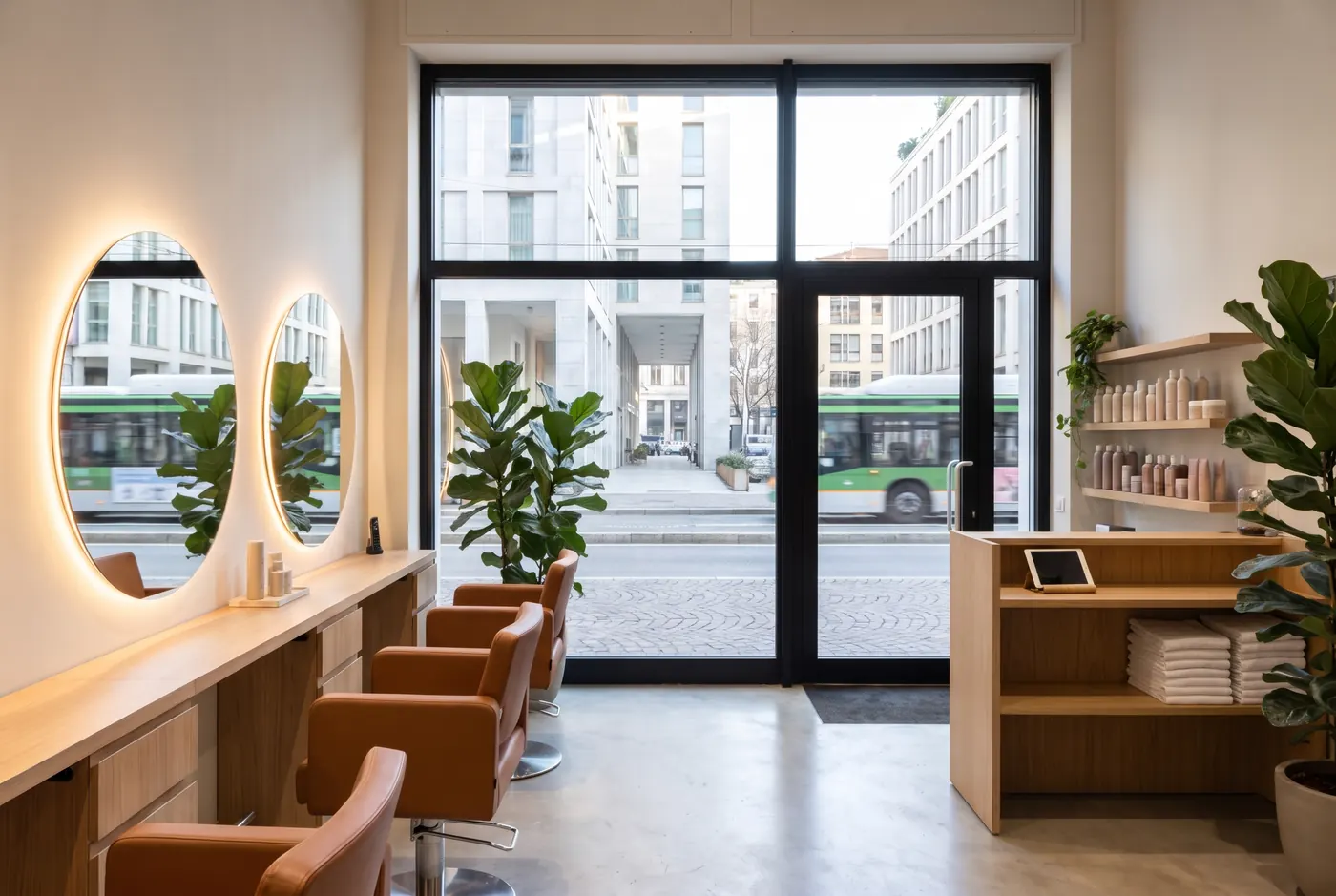 Salon interior with round mirrors, cognac chairs and a large street window
