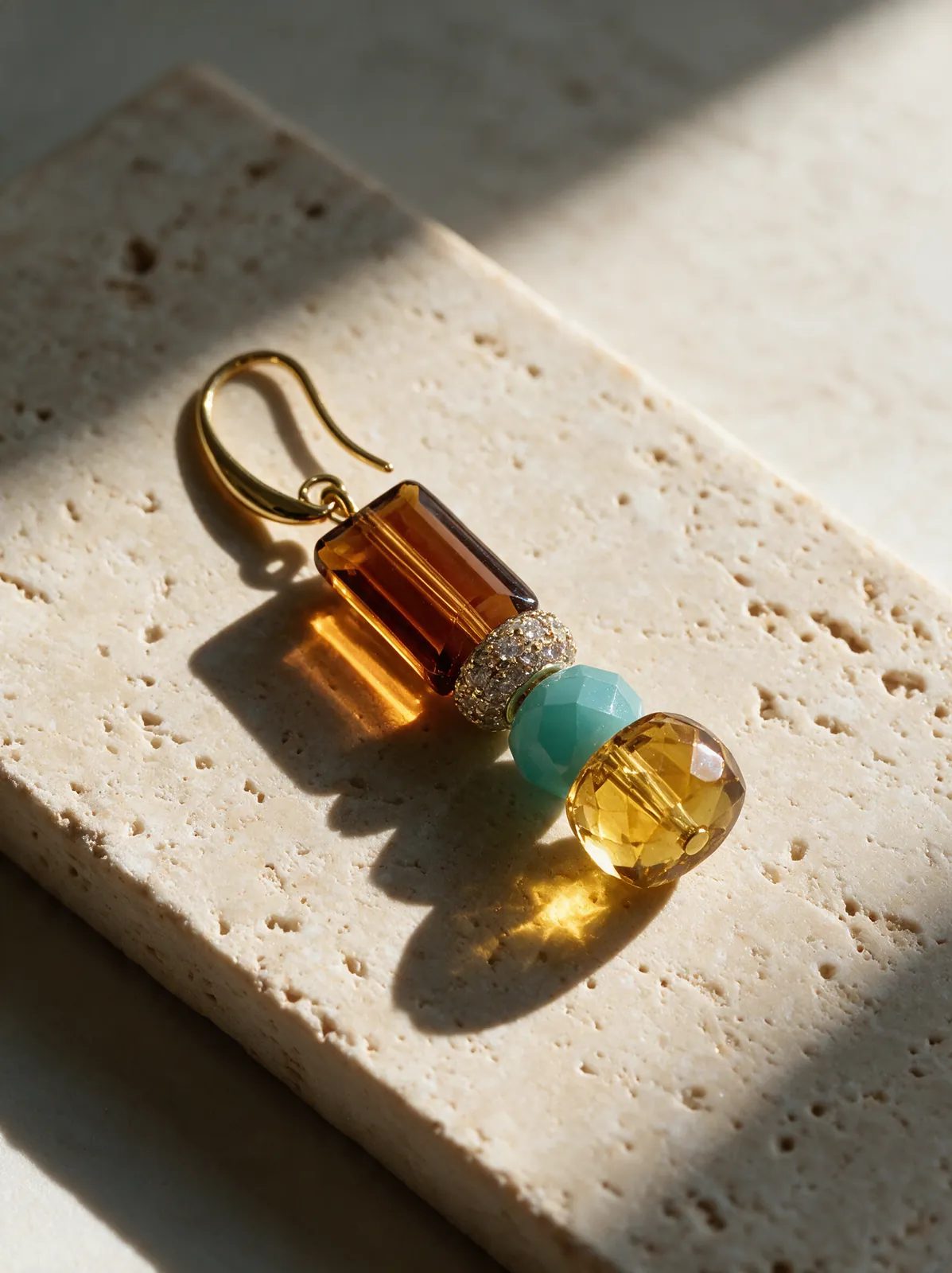 Packshot of the same earring on travertine in window light