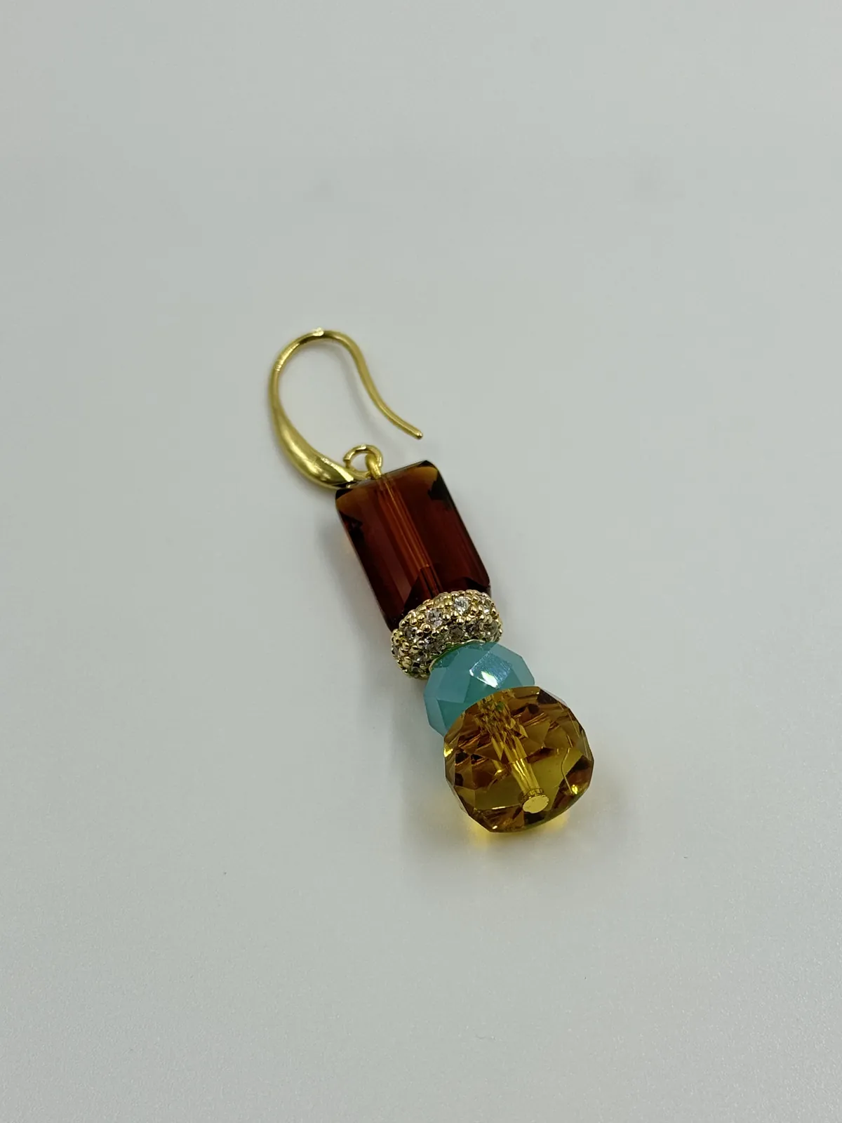 Phone photo of an amber and turquoise drop earring on a table